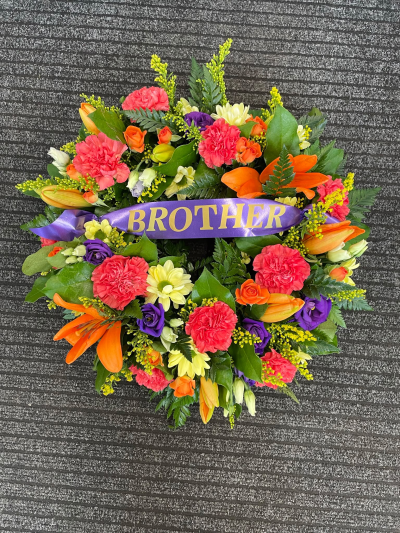 Vibrant Tribute Wreath - A vibrant personalised funeral wreath, handcrafted by Pursehouse Florist in Cannock, with a ribbon that can be customised.