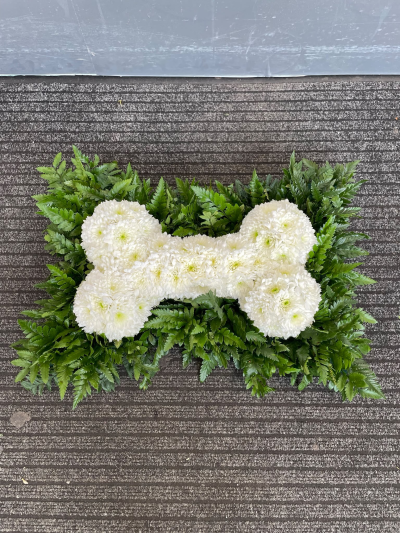 Floral Bone Tribute - A distinctive funeral cushion featuring a white floral dog bone design, handcrafted with care by Pursehouse Florist in Cannock.