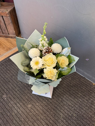 Winter Whisper - A charming arrangement featuring delicate ivory and cream tones, complemented by seasonal greenery and subtle winter-inspired touches. Beautifully presented in a gift bag, this elegant design is perfect for sending warm wishes, celebrating the festive season or simply letting someone know you're thinking of them.