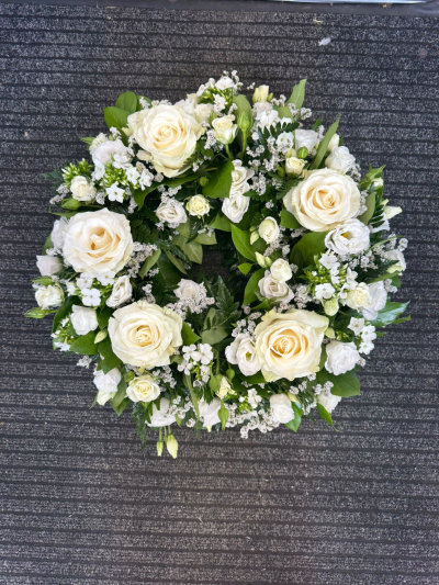Eternal Peace - A beautiful, traditional funeral wreath featuring elegant ivory and soft white tones, complemented by delicate accents and lush greenery. Lovingly arranged in a classic circular design, this timeless tribute is a heartfelt way to express your deepest sympathy and honour the memory of someone special.
