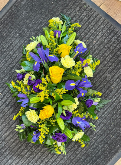 Golden Memories - A striking funeral spray featuring vibrant yellow, rich purple and soft cream tones, beautifully complemented by fresh greenery. This colourful tribute offers a meaningful way to celebrate a life filled with love and happiness while expressing your heartfelt condolences.