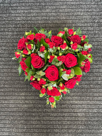 Everlasting Devotion - A stunning heart-shaped funeral tribute featuring a rich display of deep red roses, complemented by delicate greenery. Symbolising deep love, devotion and cherished memories, this beautiful arrangement offers a heartfelt and meaningful final farewell to someone who will always hold a special place in your heart.